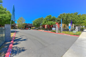 Street view of Hurley Creek entrance, bushes and trees surrounding each residential building. Photo taken on a sunny day.
