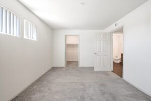 Interior unit bedroom, gray carpeting, white walls, walk in closet, bathroom located left of bedroom door.